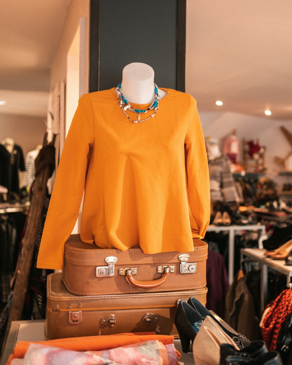 un suéter naranja de mujer y una maleta marrón