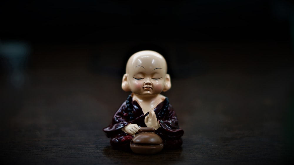 Une petite statue de Bouddha assise sur une table en bois
