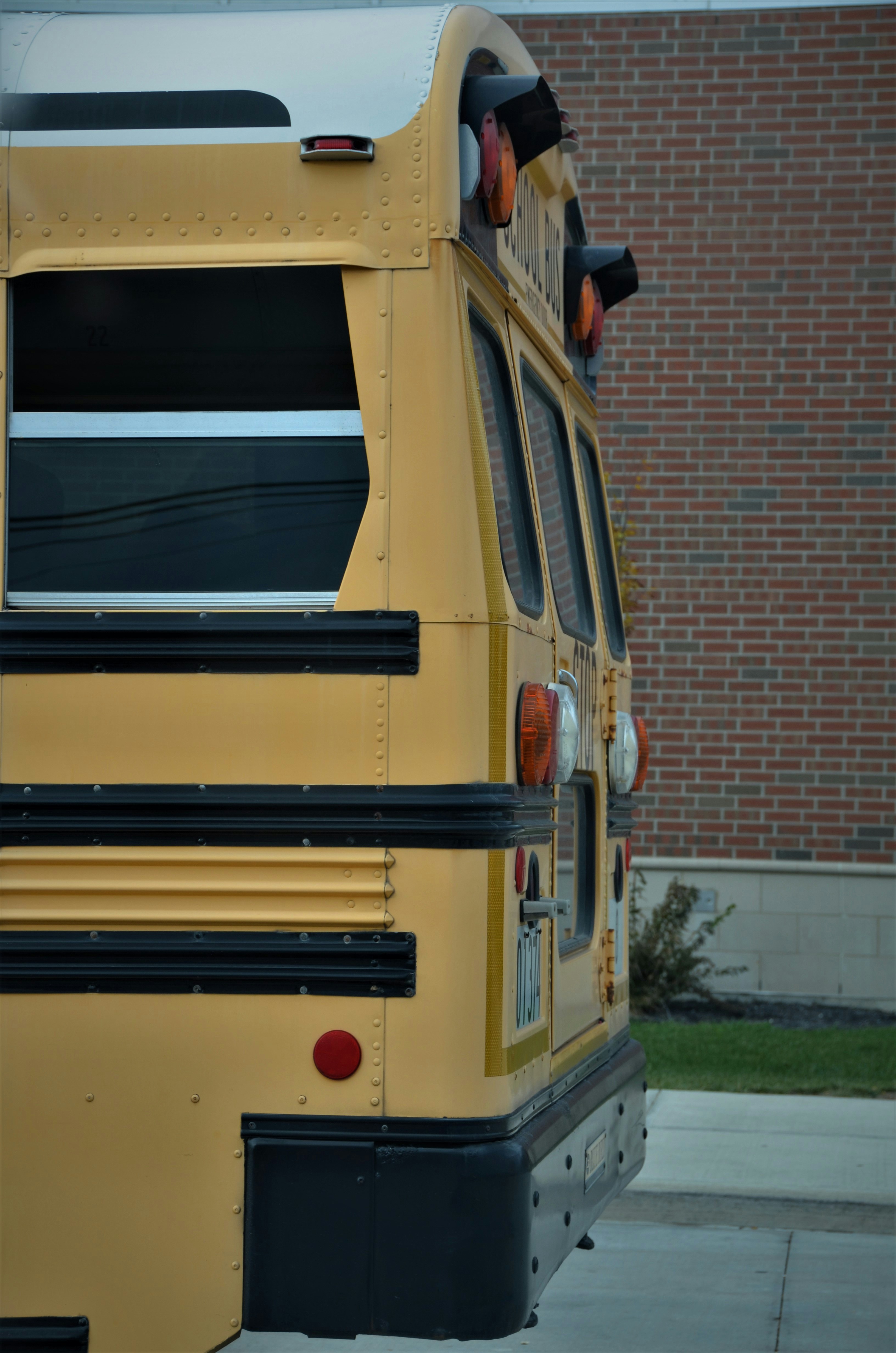 A yellow school bus parked in front of a brick building photo – Free ...