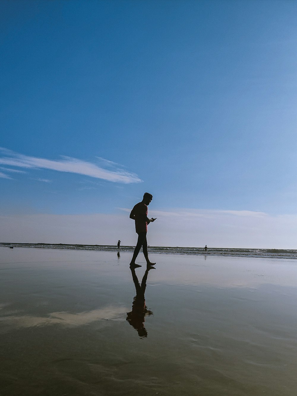 a man walking across a beach next to the ocean