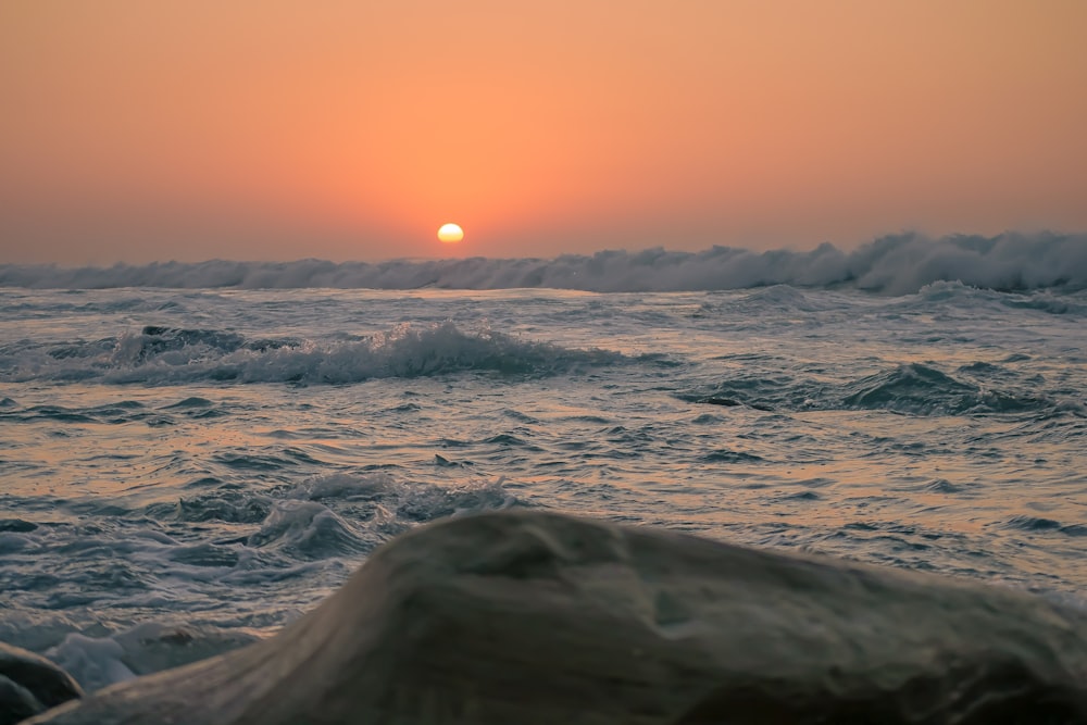 the sun is setting over the ocean waves