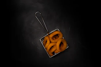 Golden onion rings and crispy bacon-topped fries served in a rustic basket.