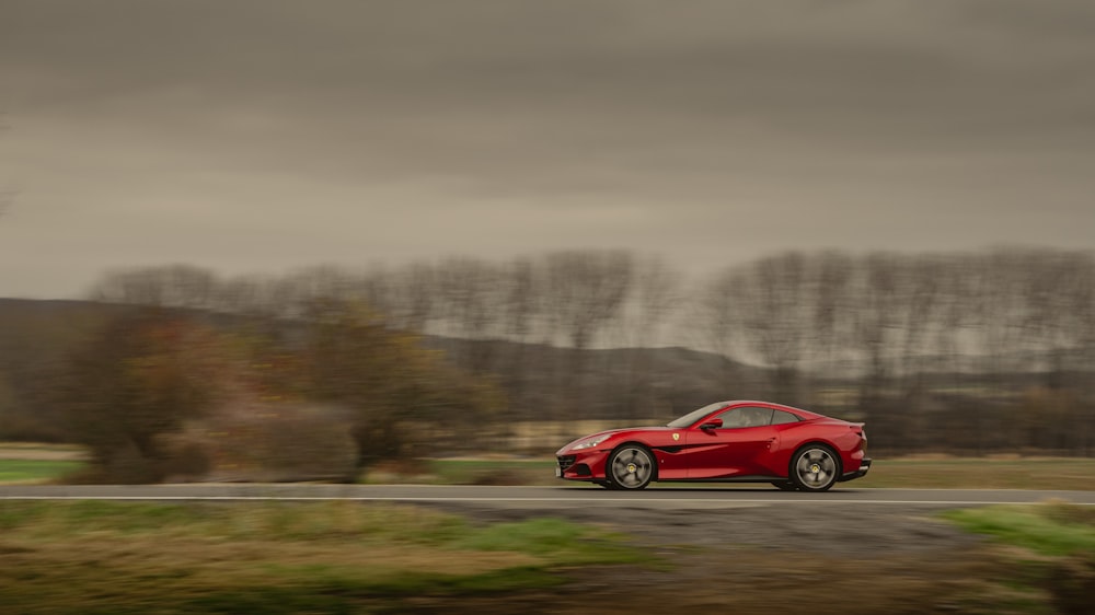 a red sports car driving down a rural road