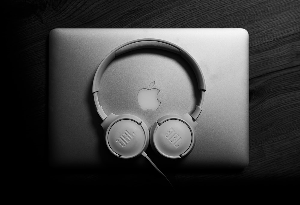 an apple laptop with headphones on top of it