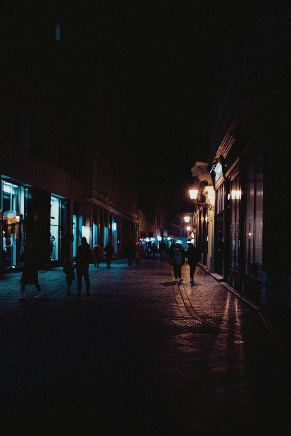 a group of people walking down a street at night