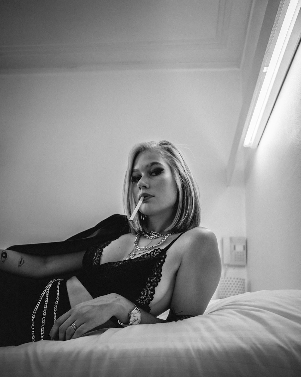 a woman sitting on a bed smoking a cigarette