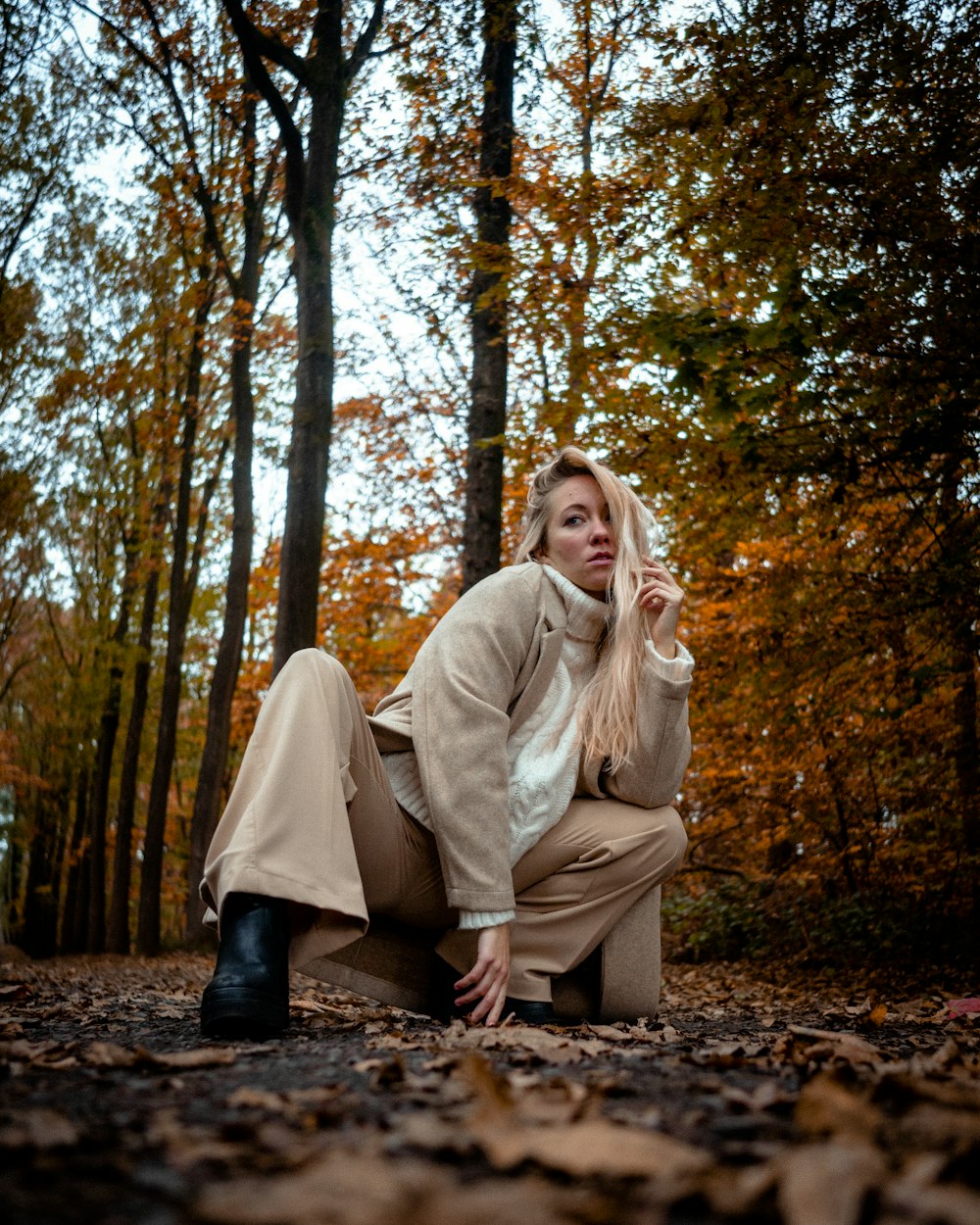 a woman sitting on the ground in the woods