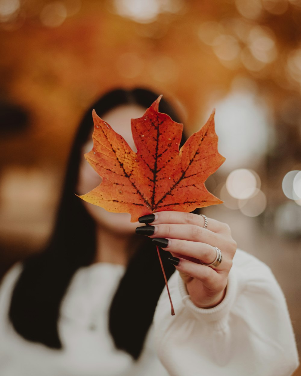 a woman holding a leaf in front of her face