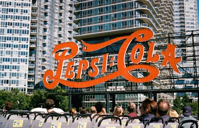a group of people sitting in front of a pepsi cola sign