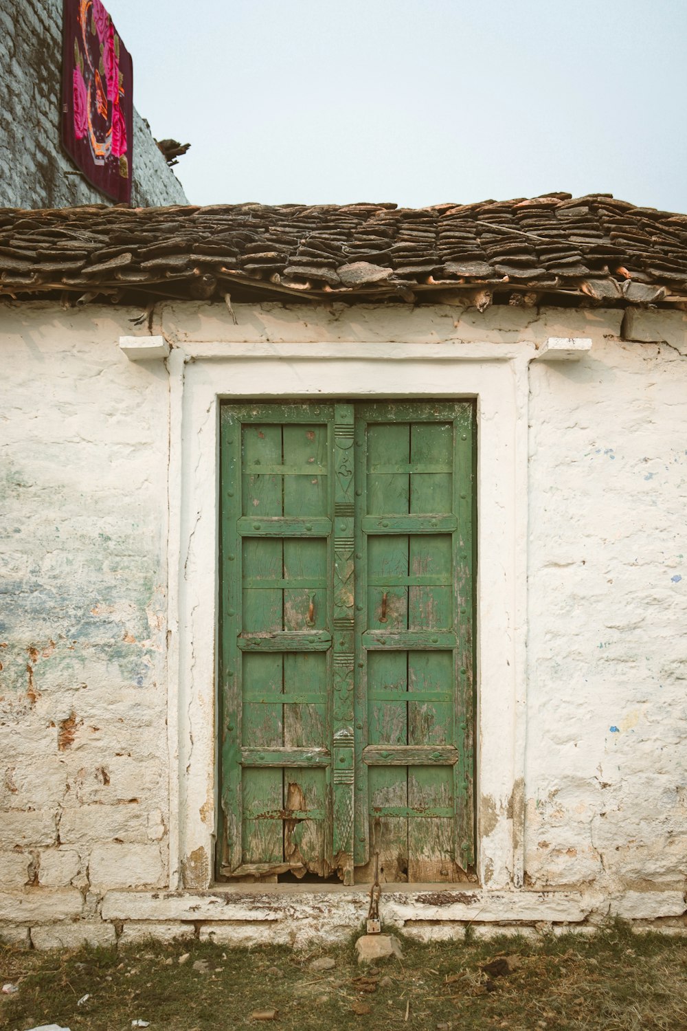 a green door on a white building with a red sign above it