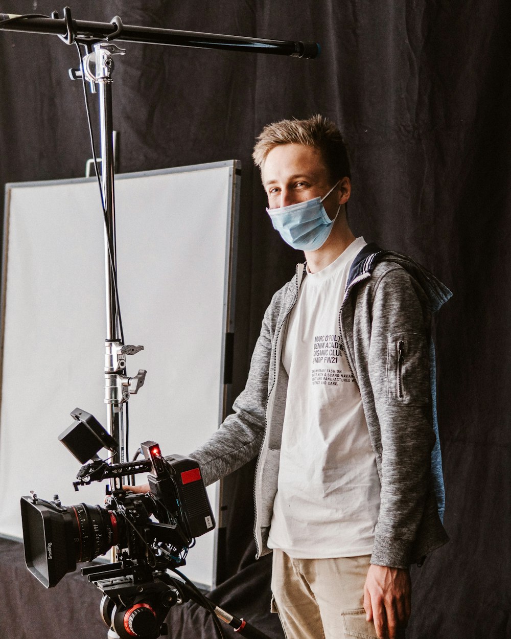 a man wearing a face mask standing in front of a camera