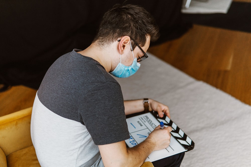 a man sitting on a bed wearing a face mask