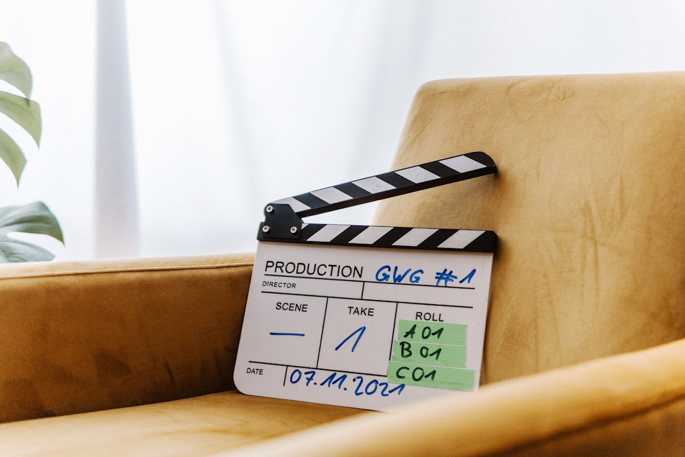 a movie clapper sitting on a chair next to a potted plant