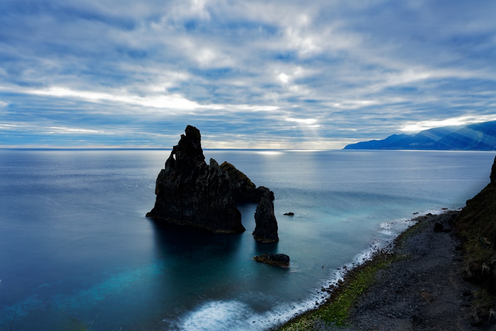 a large rock sticking out of the middle of a body of water