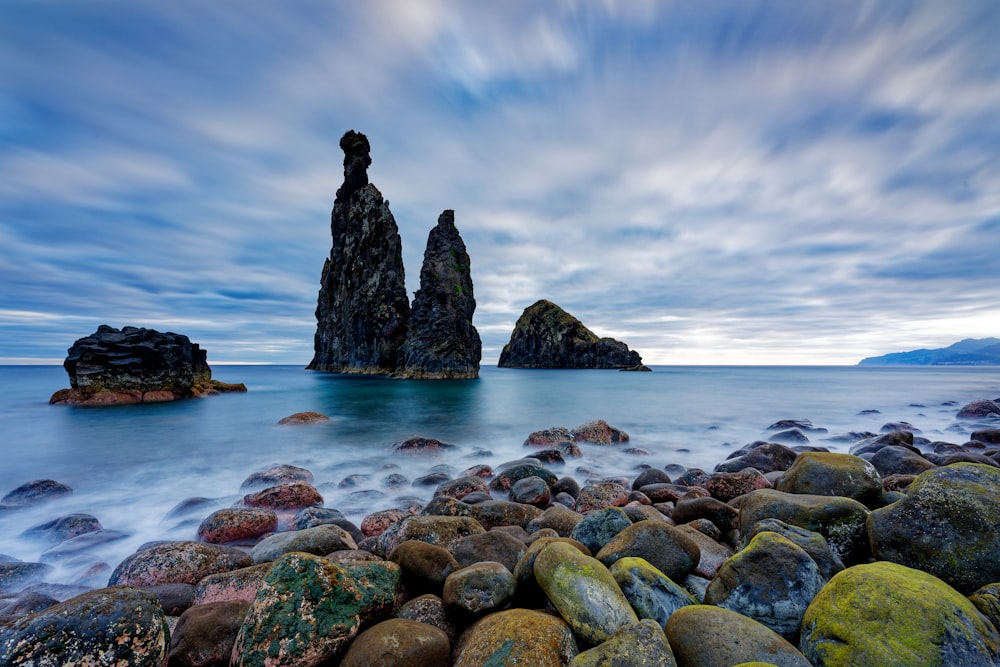 a rocky beach covered in lots of rocks under a cloudy sky