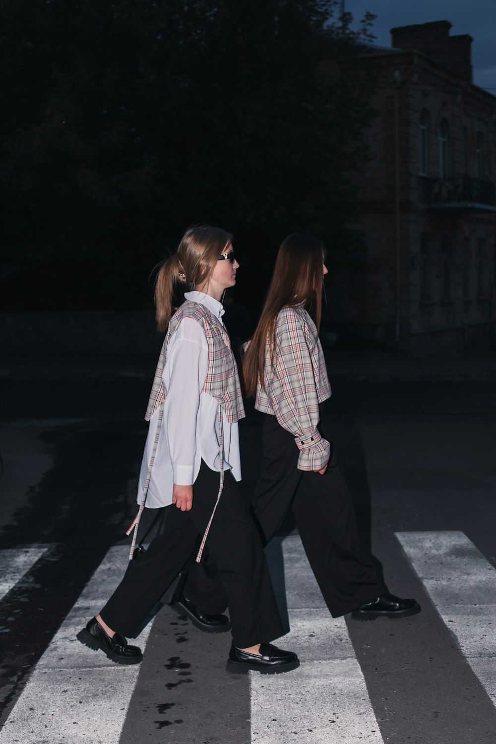 two women walking across a cross walk at night