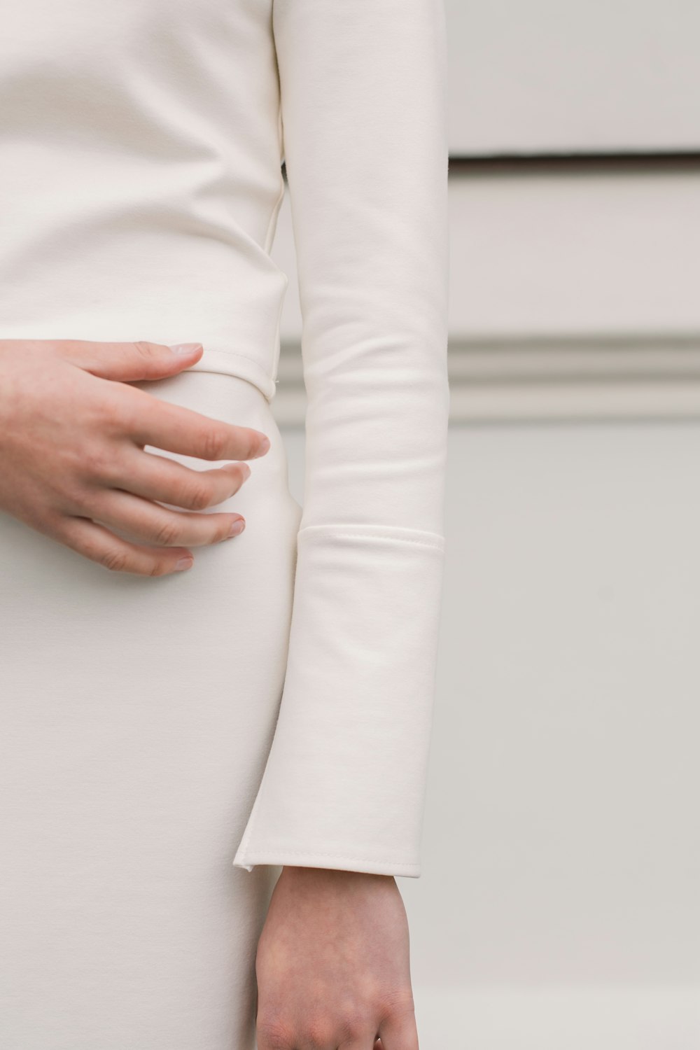 Eine Frau in einem weißen Kleid, die ihren Bauch hält