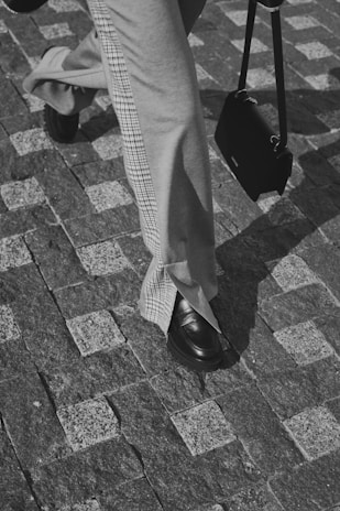 A mark bag carried by a person walking confidently down a cobblestone street.