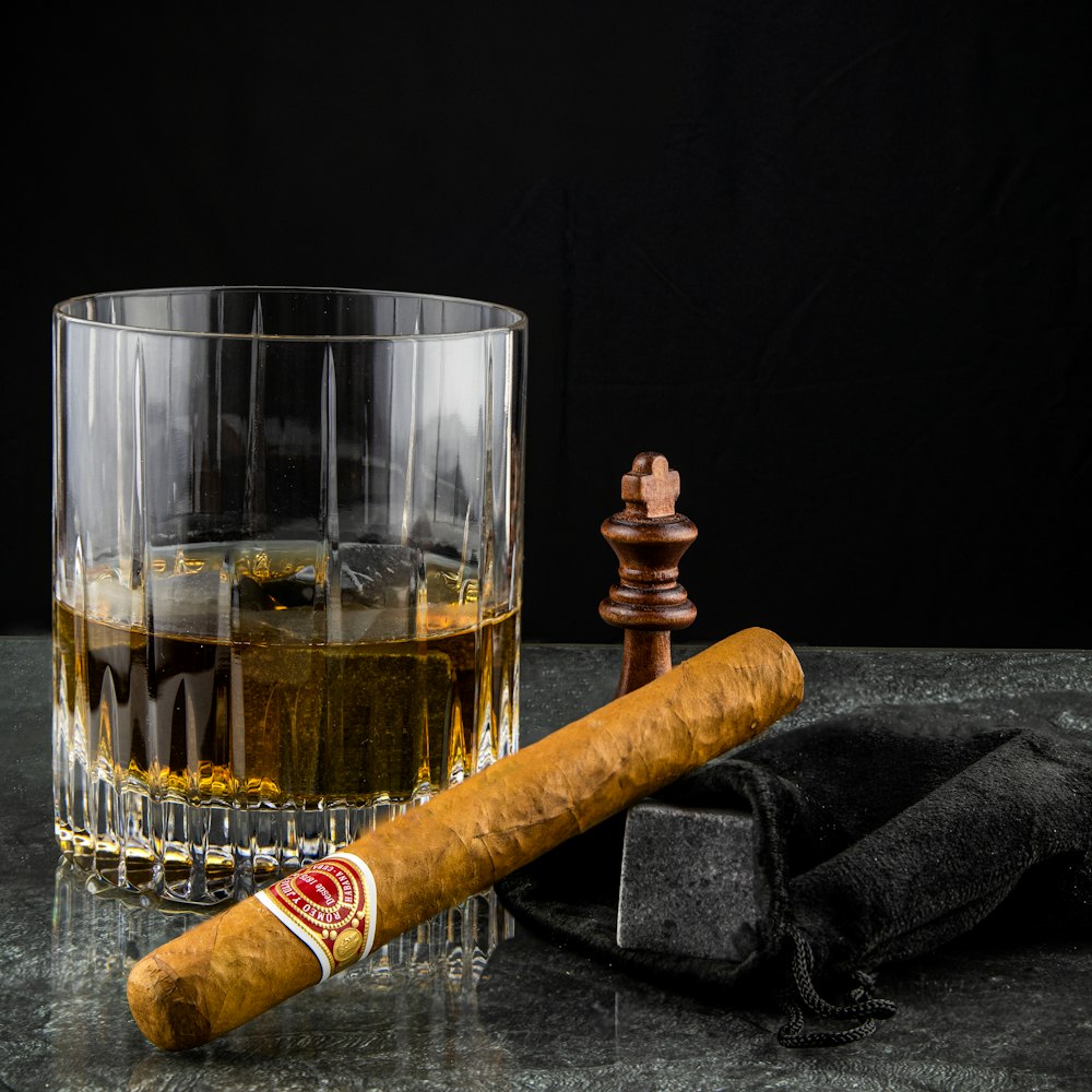 a glass of whiskey and a cigar on a table