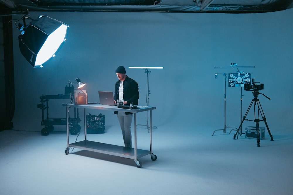 a man standing at a desk in front of a camera