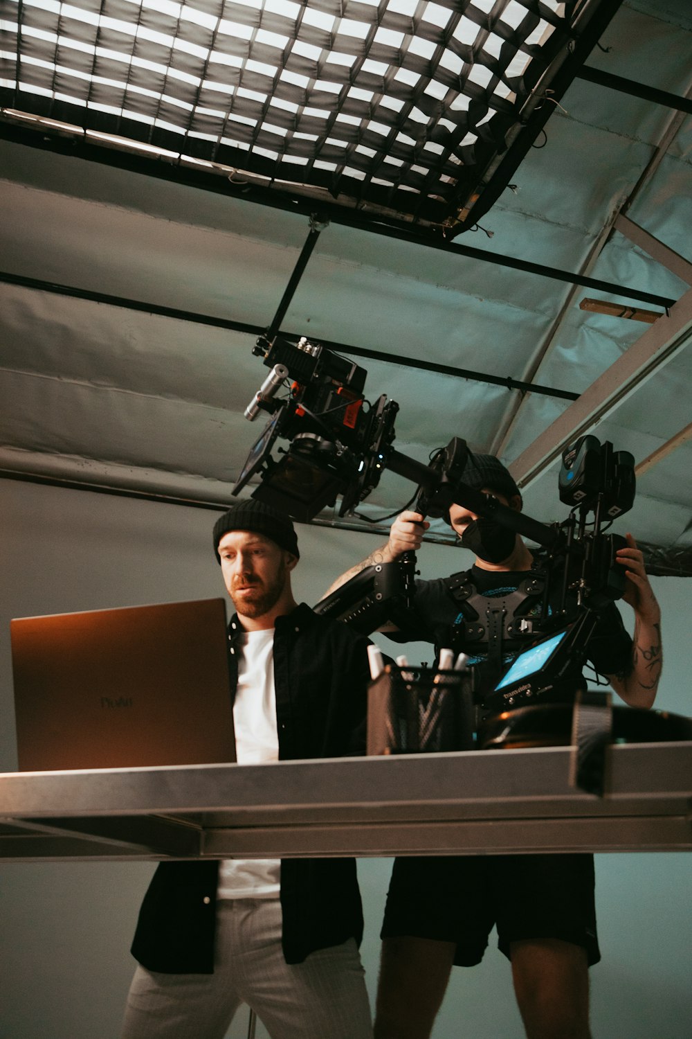a man holding a laptop while standing next to a camera