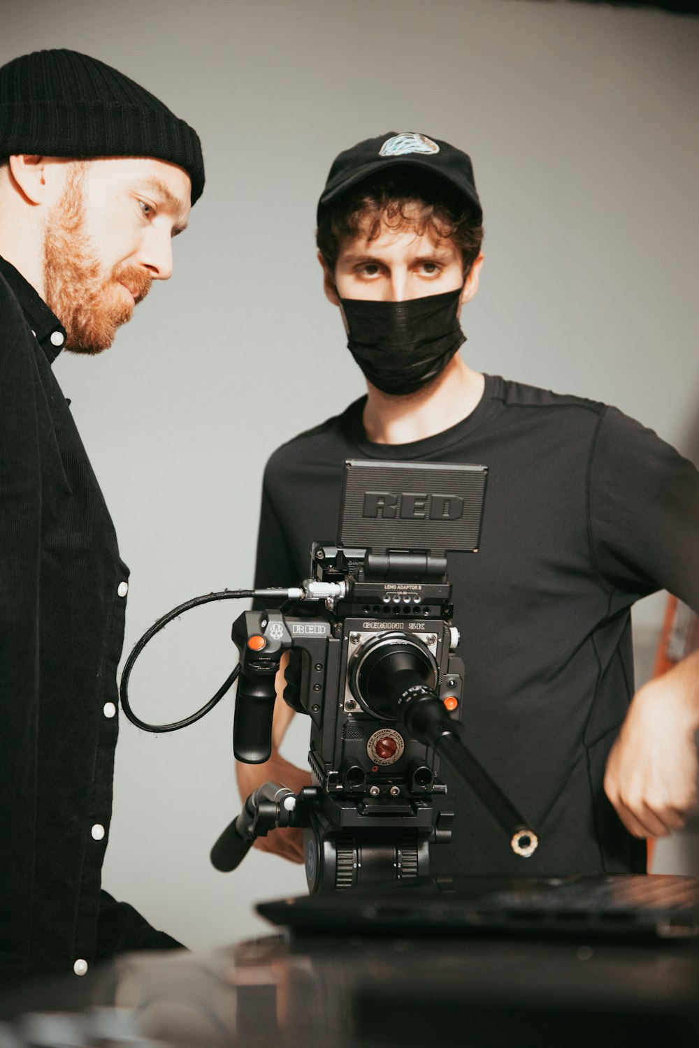 a man in a black hat and a man in a black shirt with a camera