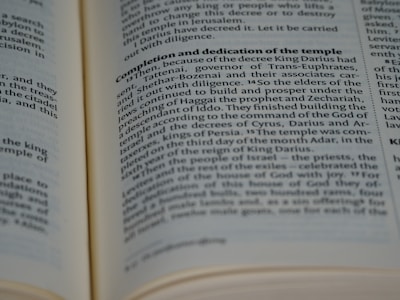 A close-up view of an open book with text in English. The page is focused on a section discussing the completion and dedication of a temple, referencing historical figures such as King Darius. The font is clear and the pages are cream-colored.