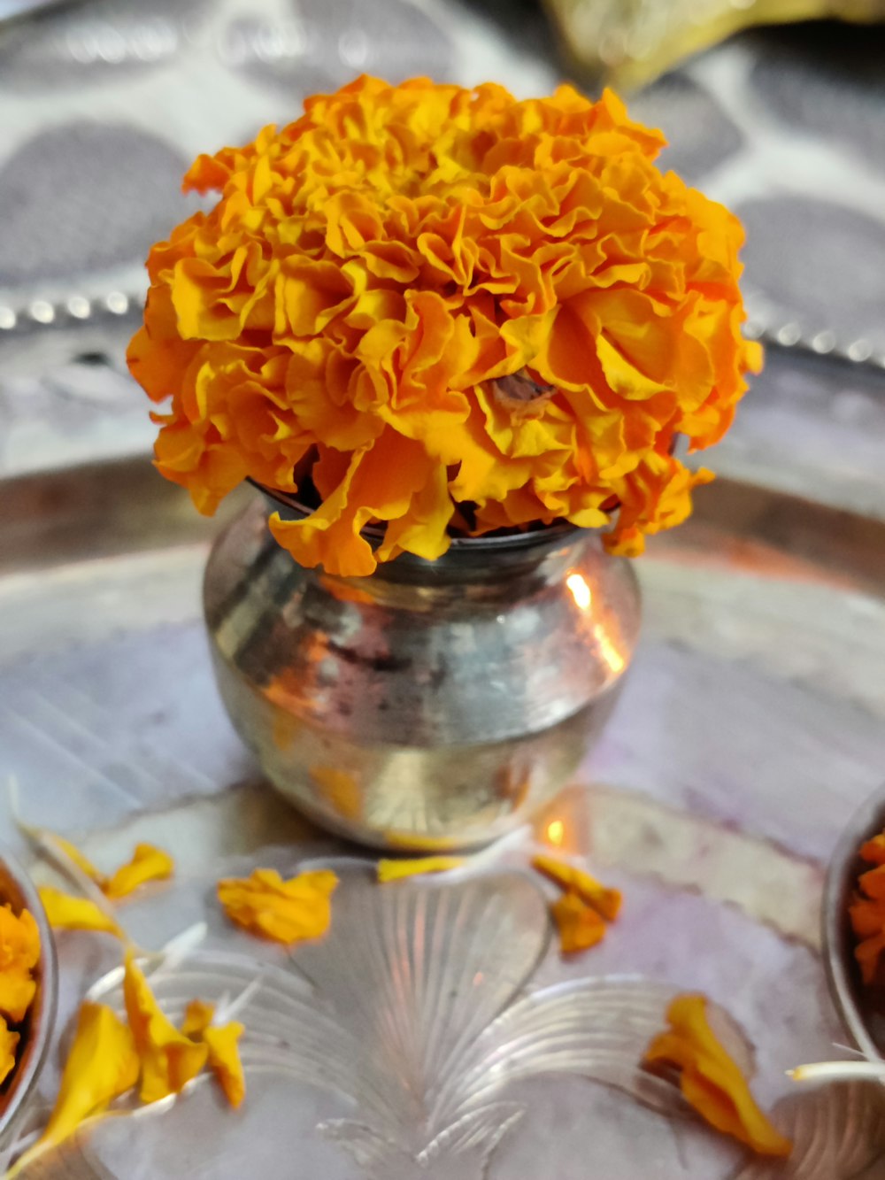 a vase filled with yellow flowers on top of a metal tray