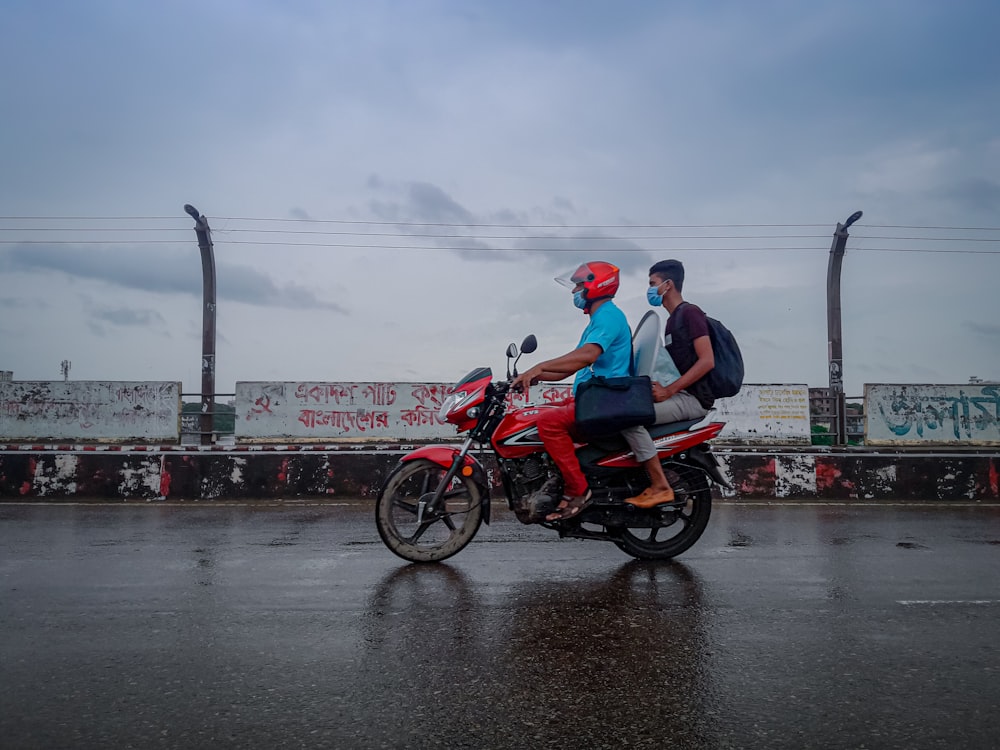 two people riding a motorcycle on a wet road
