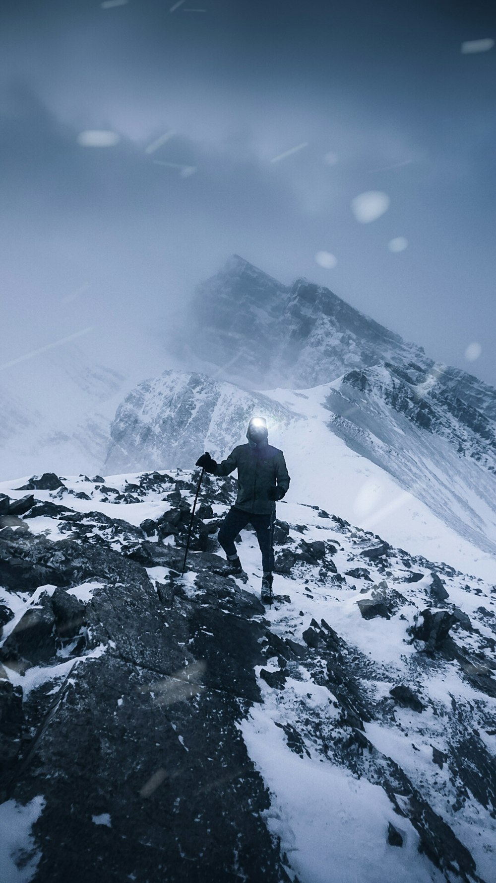 Un homme debout au sommet d’une montagne enneigée