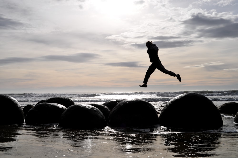 a person jumping off rocks into the ocean