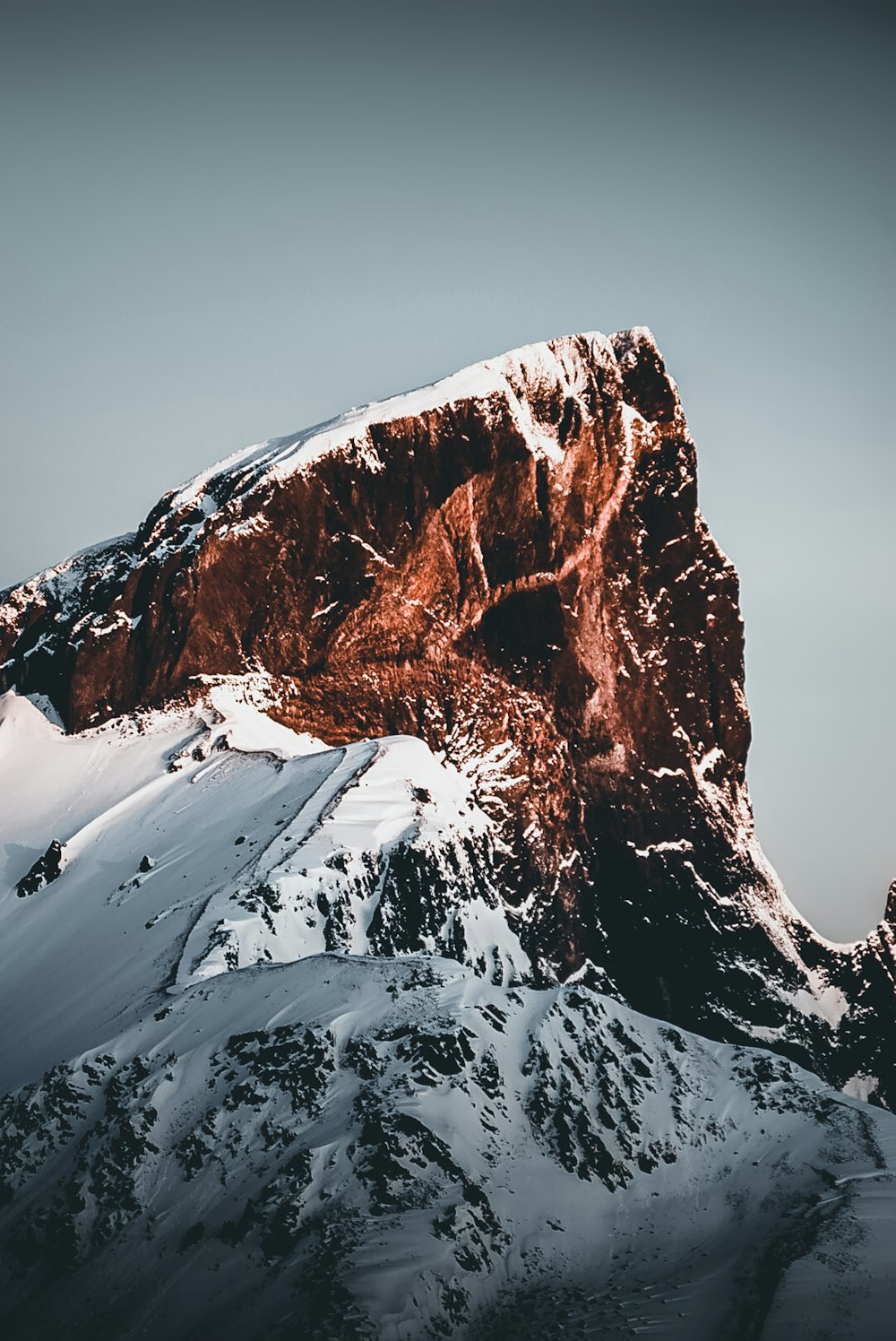 a very tall mountain covered in snow under a cloudy sky