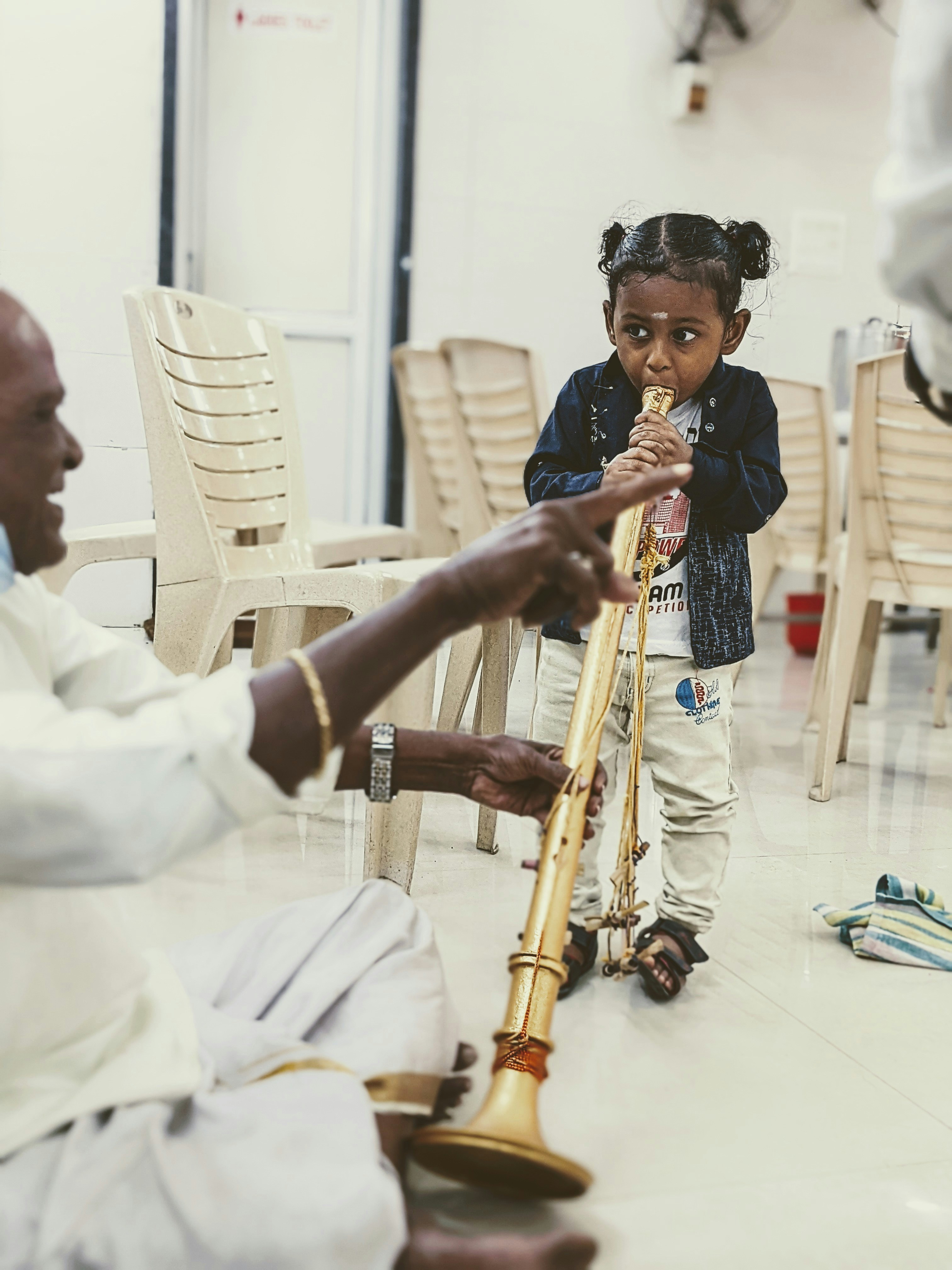 a little girl playing a flute with an older man