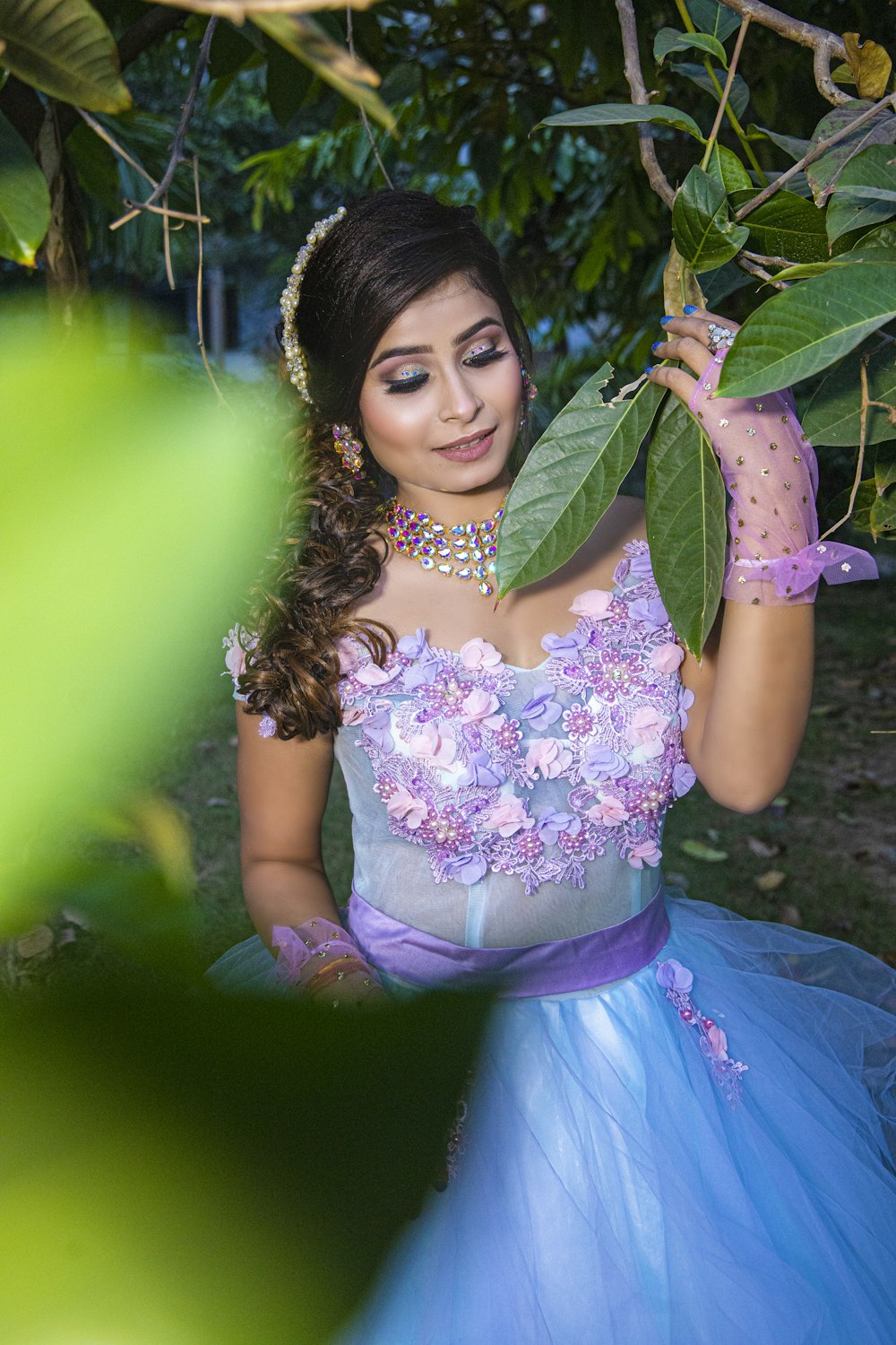 a woman in a blue dress holding a green leaf