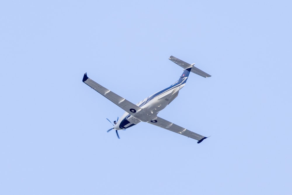 a small airplane flying through a blue sky