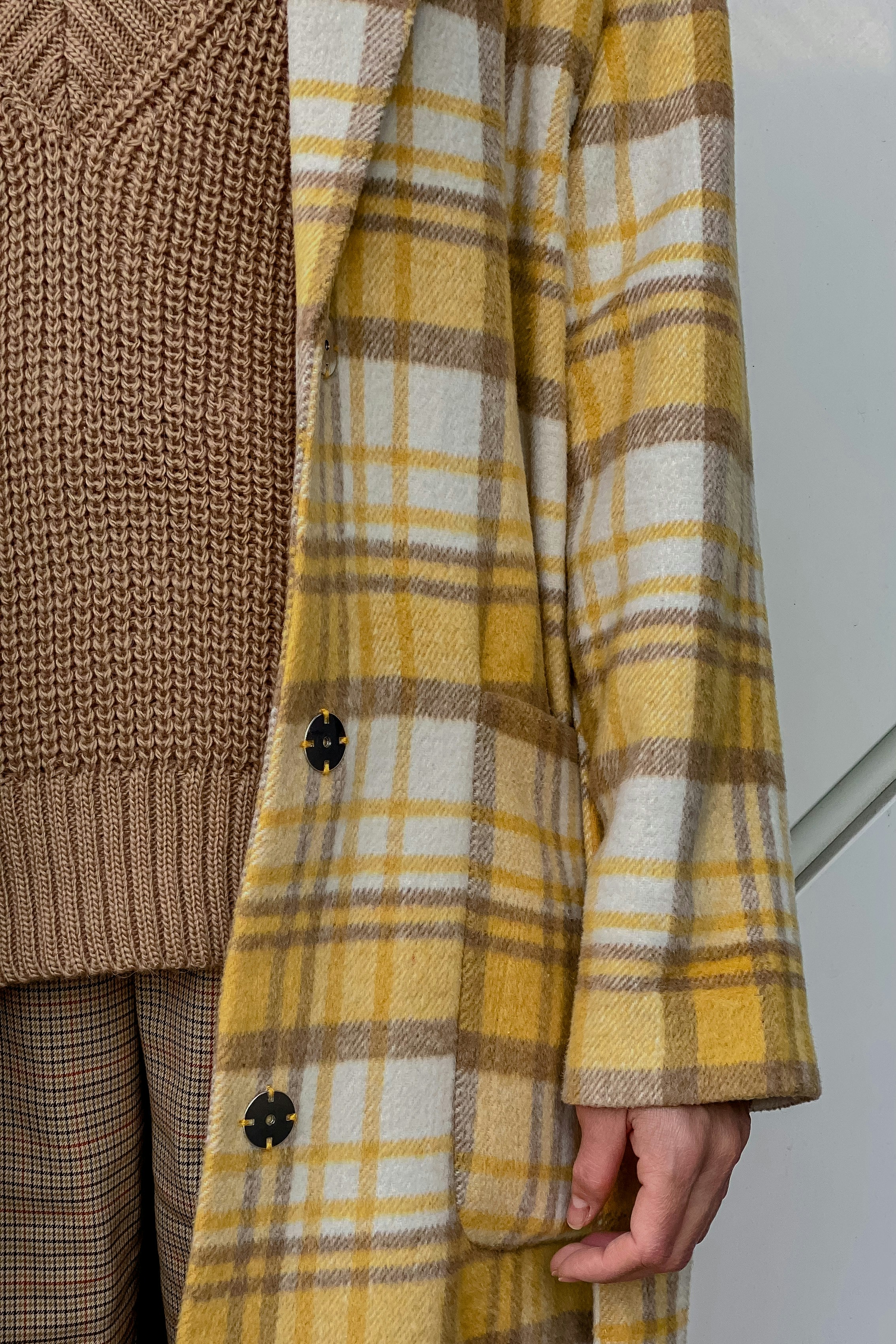 a woman wearing a yellow and brown plaid coat