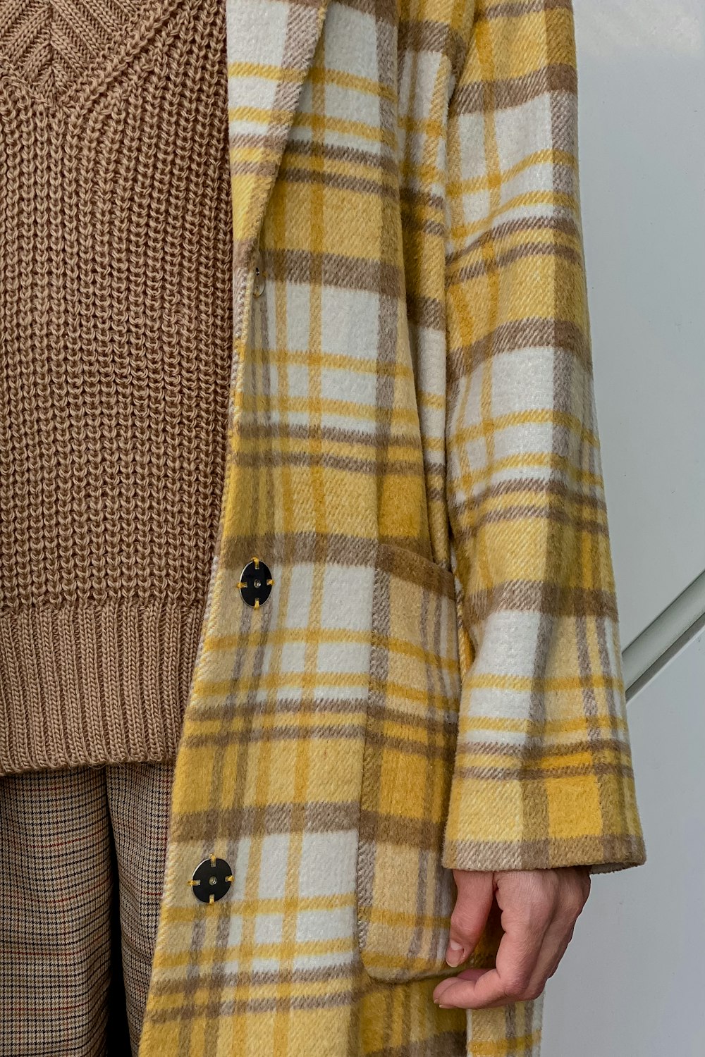 a woman wearing a yellow and brown plaid coat