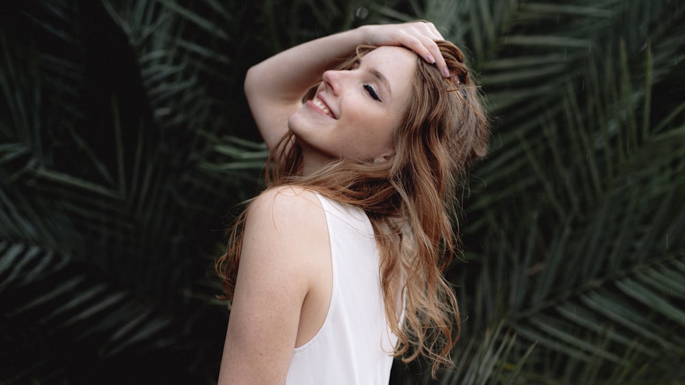 a beautiful young woman standing in front of a palm tree