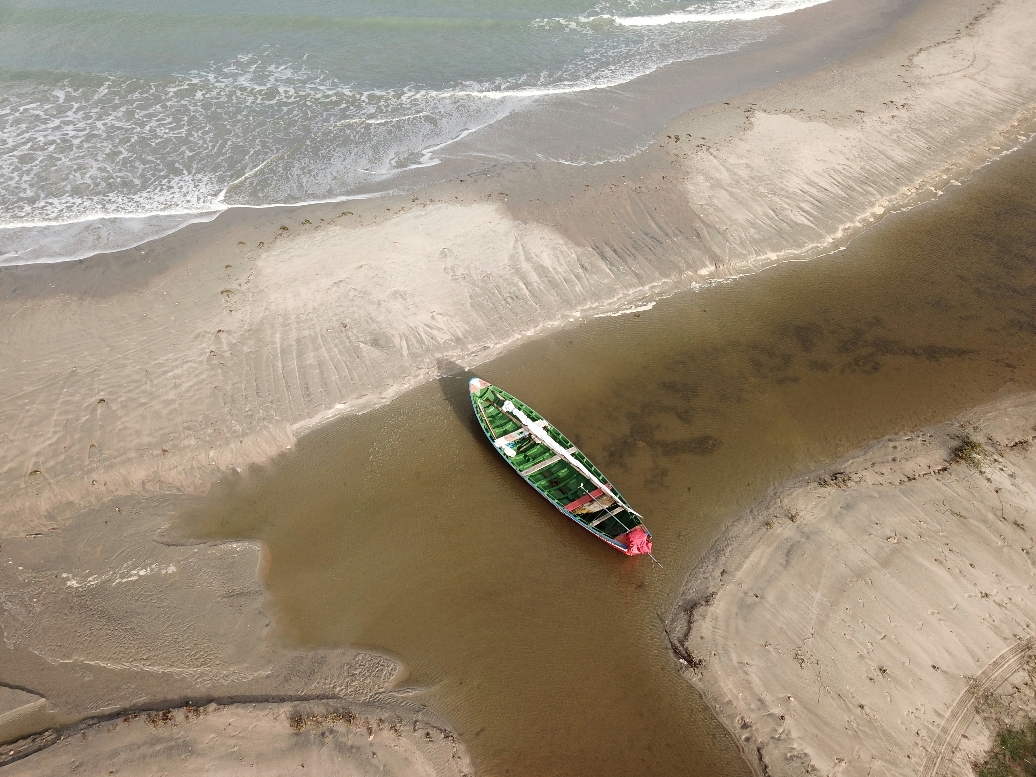a green and red boat sitting on top of a sandy beach, Boat at Jericoacoara beach
