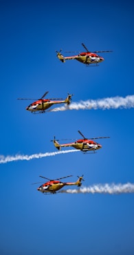 a group of four airplanes flying through a blue sky