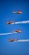 a group of four airplanes flying through a blue sky