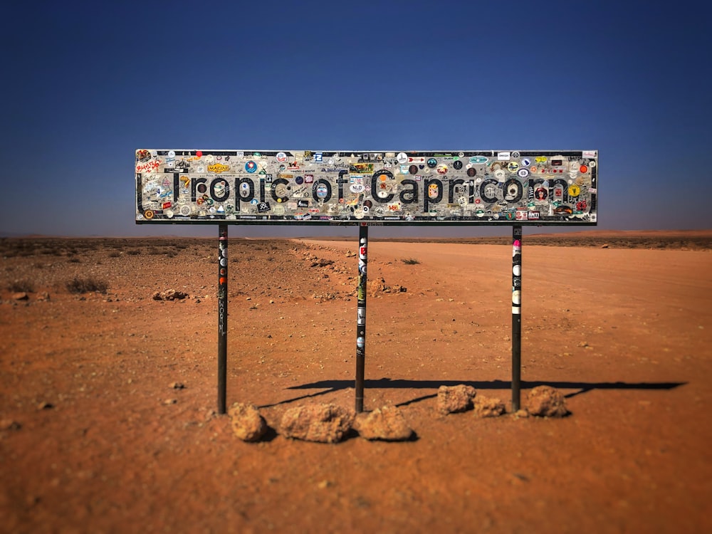 a sign in the middle of the desert with a lot of stickers on it