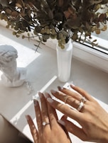 Hands wearing stylish rings with natural light highlighting details.