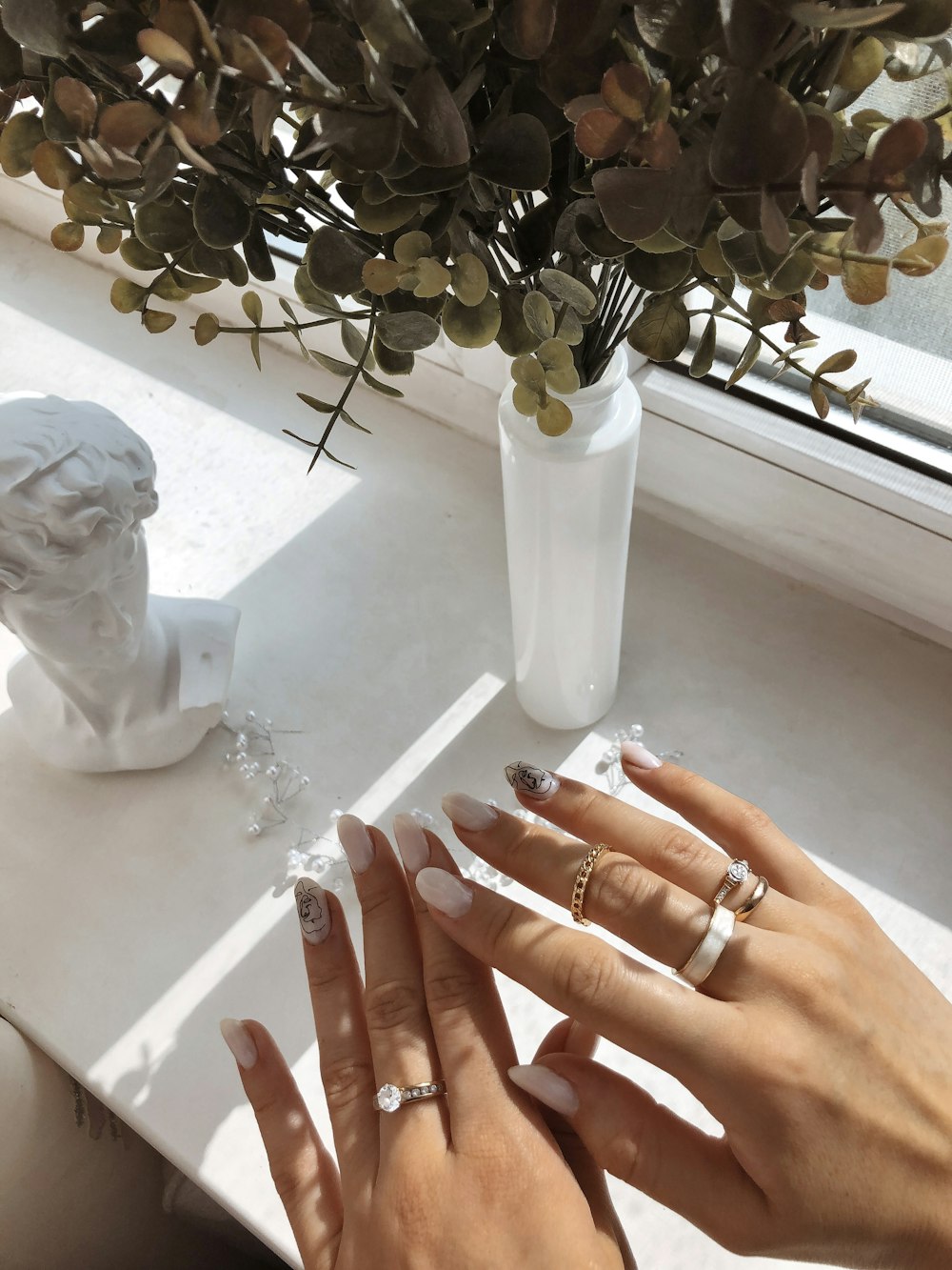 a woman's hands on a table with a vase of flowers