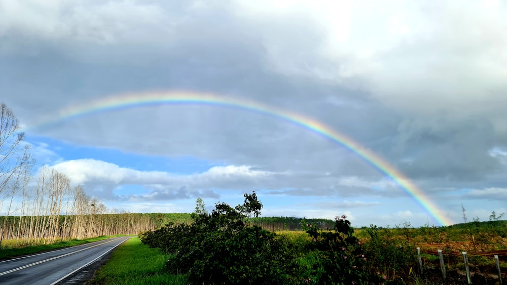 a rainbow appears over a rural country road