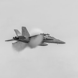 a fighter jet flying through a cloudy sky