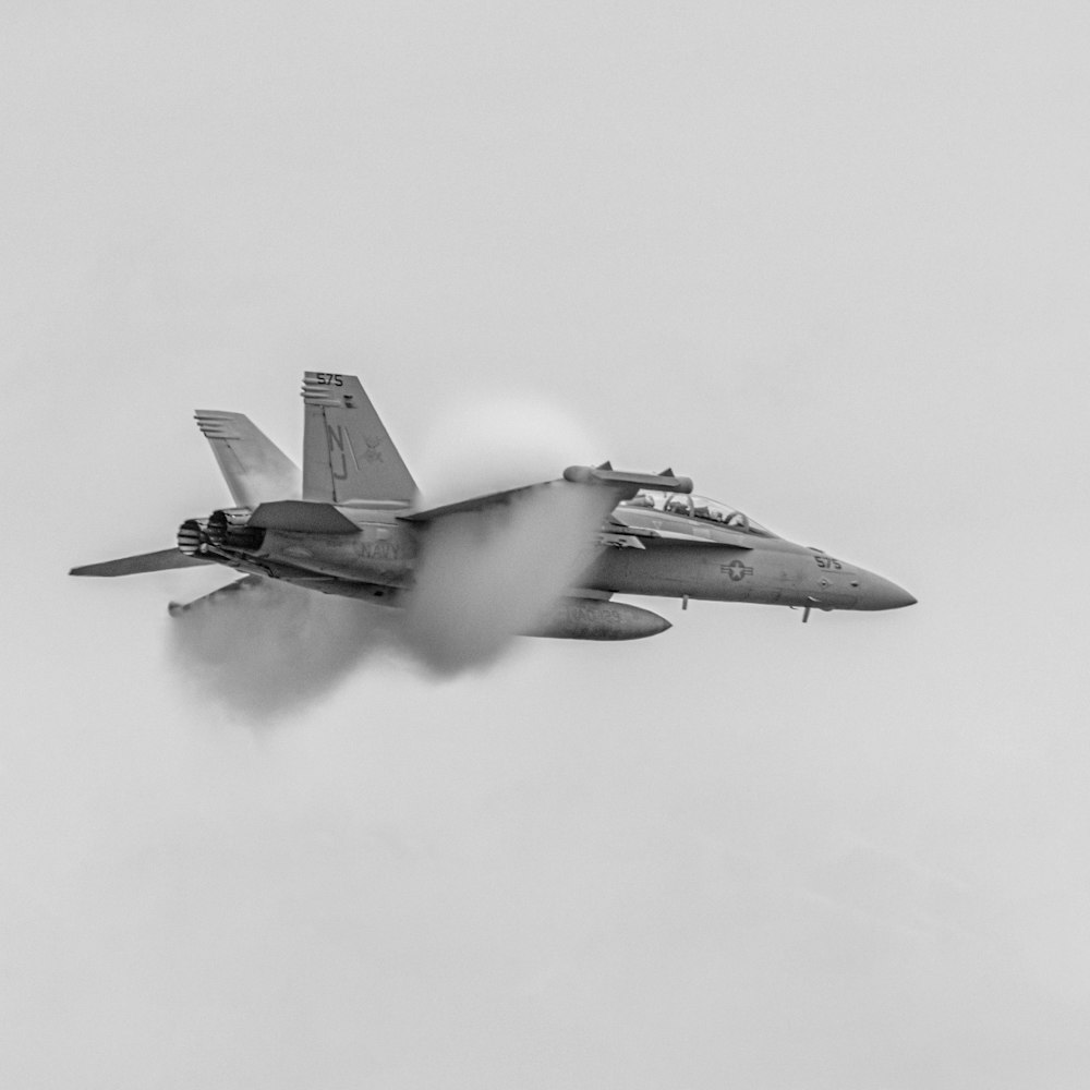 a fighter jet flying through a cloudy sky