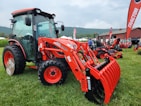 a red tractor parked on top of a lush green field