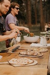 a group of people standing around a table with pizzas on it