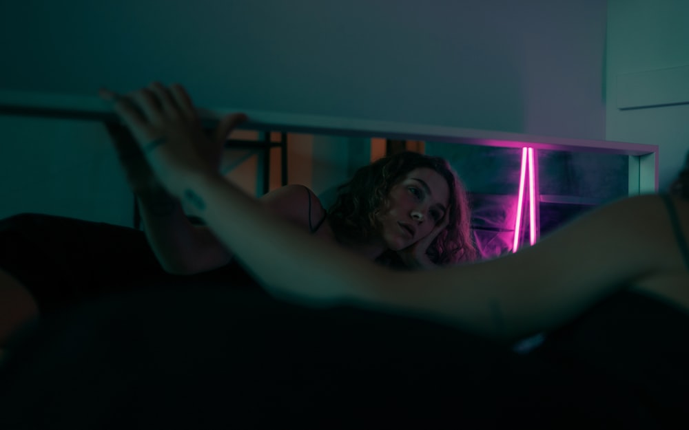a woman in a dark room looking at herself in the mirror